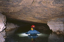 Potholer in underground cave system wading through deep water, Escudin, Huesco, Spain