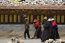 People carrying prayer wheels at Gyanag Mani wall, with millions of Tibetan mani stones, is the largest in the world. Yushu, Qinghai Province, Tibet, China