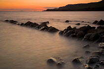 Rocks at Kimmeridge Bay at sunset, with Broad Bench, Horbarrow Bay, Brandy Bay, and Gad Cliff in the distance. Jurassic Coast World Heritage Site, Dorset, England