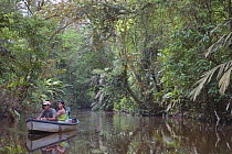 Tourists traveling by boat along river through tropical rainforest, Tortuguero National Park, Costa Rica