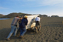 Staff and volunteers from the Marine Mammal Centre move a crated male Californian sea lion {Zalophus californianus} across the beach prior to release, Rodeo Beach, Fort Crokhite, California, USA