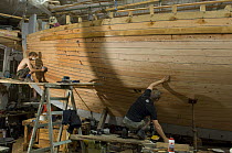Shipwrights fairing the hull of Bristol Channel Pilot Cutter "Morwenna". RB Boatbuilding, Underfall Yard, Bristol Floating Harbour, England. July 2008, Model Released
