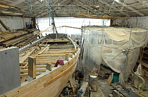 Shipwrights fairing the hull of Bristol Channel Pilot Cutter "Morwenna". RB Boatbuilding, Underfall Yard, Bristol Floating Harbour, England