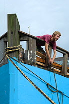 Man leaning over bow to tie up Danish fishing boat at Underfall Yard, Bristol Floating Harbour, UK. July 2008, Model Released