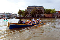 Bristol Pilot Gig Club's Men's crew practicing in their gig "Isambard" on Bristol's Floating Harbour, with the Arnolfini and city skyline in the background. England, UK. July 2008, Model Released