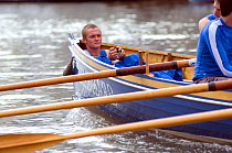 Rower hunkered down in the bow as Bristol Pilot Gig Club's Men's crew practice in their gig "Isambard" on Bristol's Floating Harbour, England, UK. July 2008, Model Released