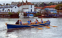 Bristol Pilot Gig Club's Ladies crew practicing in their gig "Isambard" on Bristol Floating Harbour, with the city skyline of Clifton, Brunel's Suspension Bridge and Hotwells in the background. Englan...