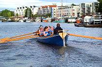 Bristol Pilot Gig Club's Ladies crew practicing in their gig "Isambard" on Bristol Floating Harbour, with city skyline in the background. England, UK. July 2008, Model Released