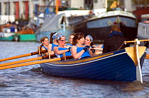 Bristol Pilot Gig Club's Ladies crew practicing in their gig "Isambard" on Bristol Floating Harbour, with moored boats in background. England, UK. July 2008, Model Released