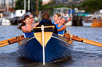 Strained faces as Bristol Pilot Gig Club's Ladies crew practice in their gig "Isambard" on Bristol Floating Harbour, with moored boats in background. England, UK. July 2008, Model Released