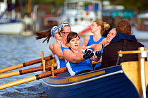 Strained faces as Bristol Pilot Gig Club's Ladies crew practice in their gig "Isambard" on Bristol Floating Harbour, with moored boats in background. England, UK. July 2008, Model Released