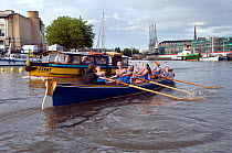 Bristol Pilot Gig Club's Ladies crew practicing in their gig "Isambard" on Bristol Floating Harbour, with city skyline and Bristol Ferry in background. England, UK. July 2008, Model Released