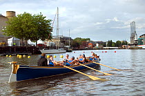 Bristol Pilot Gig Club's Ladies crew practicing in their gig "Isambard" on Bristol Floating Harbour, with city skyline in background. England, UK. July 2008, Model Released