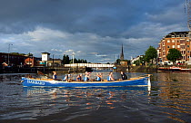 Bristol Pilot Gig Club's Ladies crew take a break from practicing in their gig "Isambard" on Bristol Floating Harbour, with city skyline in background. England, UK. July 2008, Model Released