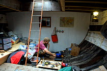 Man preparing food in hull of traditional Danish Fishing boat, Bristol Floating Harbour, UK. July 2008, Model Released