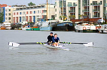 Women sculling on Bristol Floating Harbour, with city skyline in background, UK, July 2008