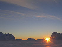 Sun rising over icebergs and pack ice, Antarctica