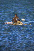 Fisherman on raft boat pulling in his net, Lake Turkana, Kenya, 2006