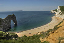 Holiday makers on the beach at Durdle Door with Portland in the distance, Jurassic Coast, Dorset, UK