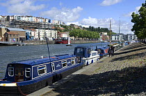 Narrowboats and cabin cruisers moored at Baltic Wharf, Bristol Harbour, UK, with Clifton Wood skyline in the background