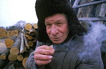 Kalinyonok smoking home grown tobacco rolled up in newspaper, Chukhrai, Bryansk Province, Russia