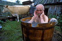 Vasily Balakhonov taking a bath in a barrel of water warmed on the stove, Chukhrai, Bryansk Province, Russia .