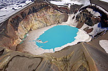 Looking down into the crater lake of the Maly Semyachik Volcano with ice at the rim and azure blue colouring caused by the acidic water, July.