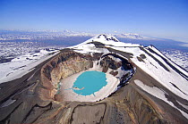 Looking down into the crater lake of the Maly Semyachik Volcano with ice at the rim and azure blue colouring caused by the acidic water, July.