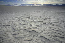 Ripples on white sand dunes running down to Alkali Flat with San Andres Mountains behind, White Sands National Park, Chihuahuan Desert, New Mexico, USA