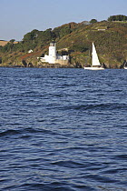 Sloop sailing past St. Anthony's Head lighthouse at the mouth of Falmouth Harbour, Cornwall, UK
