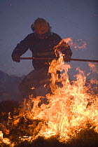 Fireman beating out a grass fire on moorland, Lancashire, UK