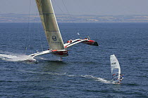 Multihull "Brossard" heeling, with windsurfer in foreground, during Defi Petit Navire race, Douarnenez, France. July 2006