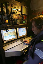 Skipper Bruno Peyron at chart-plottig table on Maxi-catamaran "Orange II", Jules Verne Trophy January 2005