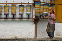 Womanturnign prayer wheels in Tashiding Monastery, Sikkim, India October 2007