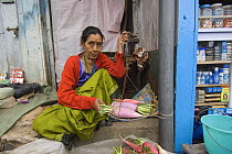 Woman weighing root vegetables at street market,  Sombare, West Sikkim, India October 2007