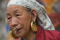 Woman (of Nepali origin) wearing gold jewellery in nose and ears at the street market of Sombare, West Sikkim, India October 2007