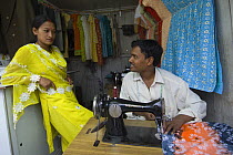 Tailor and woman with sewing machine in street market of Sombare, West Sikkim, India October 2007