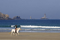Horse rider on beach at Trepasses Bay, with Cape Sizun, the Pointe du Raz and La Veille Lighthouse. October 2007.