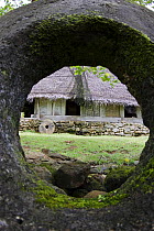 Men's house / falluw viewed through circular stone hole in a village on the Island of Yap, Micronesia. September 2007. ^^^ Fallows are constructed of large logs, bamboo, and thatch and are where visit...