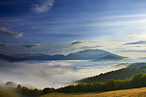 Mist lying on the Piano Grande at dawn with the mountains of Monti Sibillini National Park rising above, Umbria, Italy