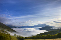 Mist lying on the Piano Grande at dawn with the mountains of Monti Sibillini National Park rising above, Umbria, Italy