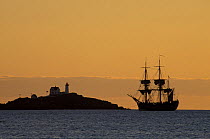 Silhouette of replica of Captain Cook's SS Endeavor and Cape Nedick Lighthouse, York, Maine, USA