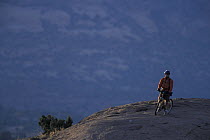 Mountain biking on the Moab Slickrock Bike Trail, Navajo Sandstone, La Sal Mountains in background. Utah, USA