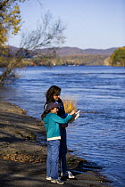 Mother and daughter identifying birds and birdwatching on the banks of the Connecticut River in Holyoke, Massachusetts, USA, model released