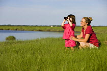 Mother and daughter birdwatching in the tidal estuary of Plum Island Sound, Sawyer's Island,  Massachusetts, USA. model releaese