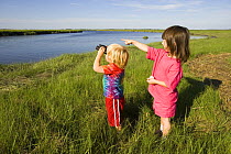 Two children birdwatching, Plum Island Sound, Rowley, Massachusetts, USA. model released
