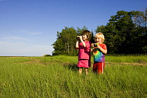 Two children birdwatching, Plum Island Sound, Rowley, Massachusetts, USA. model released