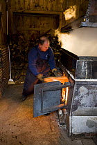 Tending the fire under a sap evaporator in a sugar house in Barrington, New Hampshire, USA. the Sugar Shack, manufacture of maple syrup.