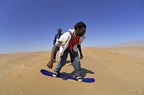 Sand boarding down a sand dune, near Swakopmund, Namib Desert, Namibia  2007