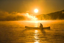 Canoeing in Lily Bay iin the mist at sunrise, Moosehead Lake, Maine, USA.  model released
